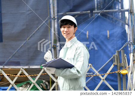 一名微笑的亞洲工人在建築工地擺出勝利姿勢。 142965837