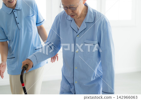 An elderly man with a cane and a caregiver An elderly man with a cane and a caregiver 142966063