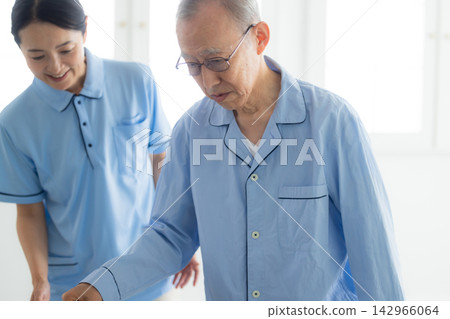 An elderly man with a cane and a caregiver An elderly man with a cane and a caregiver 142966064