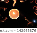 Low Angle View of People Releasing a Glowing Paper Sky Lantern into the Night Sky 142966876