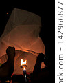 People Lighting a Paper Sky Lantern Together Before Release at Night Festival 142966877