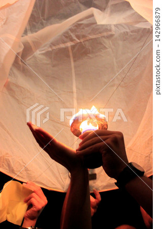Hands Lighting the Fuel Burner of a Paper Sky Lantern During Night Festival Hands Lighting the Fuel Burner of a Paper Sky Lantern During Night Festival 142966879