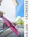 A Japanese umbrella stands out quietly in front of a white-walled storehouse. 142966938