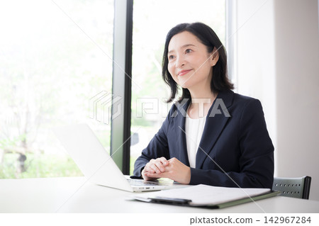 Image of a smiling Japanese woman in her 50s, a financial planner, explaining business, including reviewing mortgage interest rates. Image of a smiling Japanese woman in her 50s, a financial planner, explaining business, including reviewing mortgage interest rates. 142967284