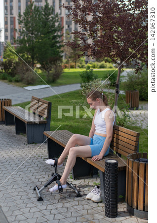 A woman uses Pedal Exercise Machine for self-rehabilitation outdoors. A woman uses Pedal Exercise Machine for self-rehabilitation outdoors. 142967310