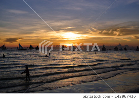 Tropical Sunset Seascape with Silhouettes of Sailing Boats and a Child Tropical Sunset Seascape with Silhouettes of Sailing Boats and a Child 142967430