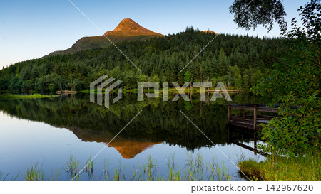 Mountain Lake Reflection with Forest and Wooden Dock at Golden Hour 142967620
