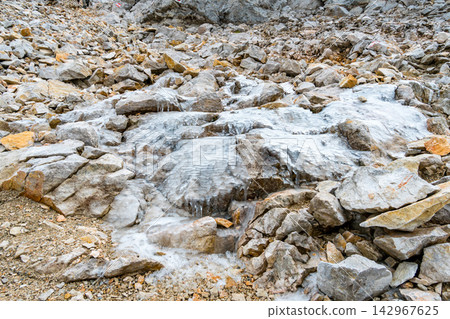 Frozen Rocky Mountain Stream with Ice and Rugged Alpine Terrain Frozen Rocky Mountain Stream with Ice and Rugged Alpine Terrain 142967625