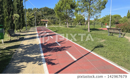 Red bike path park infrastructure background. Bicycle lane outdoor summer recreation. Fun fitness hobby active lifestyle backdrop. Red bike path park infrastructure background. Bicycle lane outdoor summer recreation. Fun fitness hobby active lifestyle backdrop. 142967679