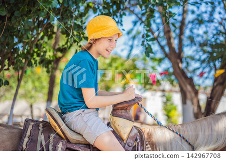 Child laughs with delight during a recreational horse ride. Happy riding experiences and outdoor family fun. Child laughs with delight during a recreational horse ride. Happy riding experiences and outdoor family fun. 142967708