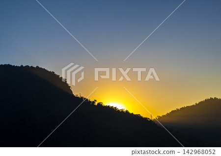 Golden colorful sunrise behind the tropical mountain mountains in Brazil. Golden colorful sunrise behind the tropical mountain mountains in Brazil. 142968052