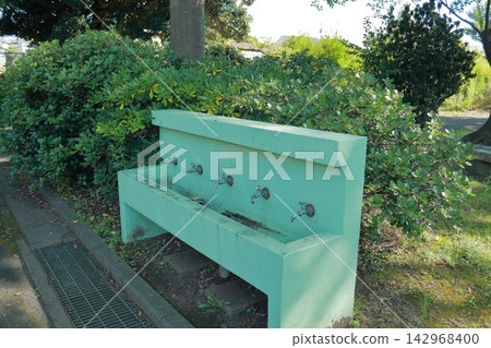 Concrete drinking fountain with multiple taps in a park; outdoor public facility. Concrete drinking fountain with multiple taps in a park; outdoor public facility. 142968400