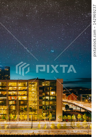 Stunning night panorama of the modern illuminated Barcode Project skyscrapers along Dronning Eufemias gate under a starry sky in Bjorvika, Oslo. 142969237