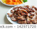 Roasted pork slice on white plate with vegetables in background 142971720