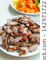 Roasted pork slice served on white plate with pickled vegetable garnish 142971722