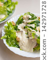 Creamy salad with lettuce, dressing, crouton, and cheese served on plate 142971728