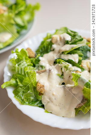 Creamy salad with lettuce, dressing, crouton, and cheese served on plate Creamy salad with lettuce, dressing, crouton, and cheese served on plate 142971728