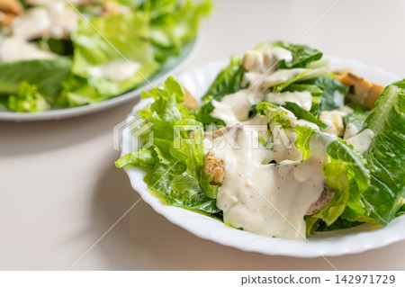 Creamy romaine salad with grilled chicken and dressing served on white plate Creamy romaine salad with grilled chicken and dressing served on white plate 142971729