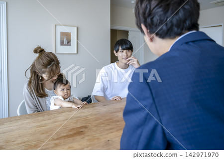 一個年輕家庭和一位銷售代表正在討論購買公寓的事宜。 142971970