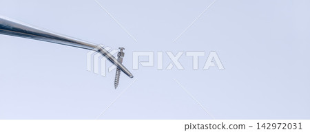 Orthodontic mini implant screw held with dental tweezers for temporary anchorage device placement and modern orthodontic treatment Orthodontic mini implant screw held with dental tweezers for temporary anchorage device placement and modern orthodontic treatment 142972031