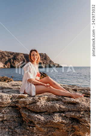 Woman beach vacation sitting on coastal rocks overlooking the blue sea during summer sunset holiday with copy space Woman beach vacation sitting on coastal rocks overlooking the blue sea during summer sunset holiday with copy space 142973032