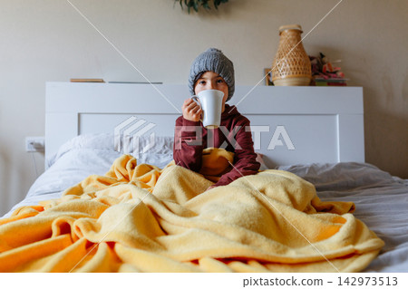 Portrait of Child Drinking Hot Drink in Bed, Feeling Cold at Home Portrait of Child Drinking Hot Drink in Bed, Feeling Cold at Home 142973513