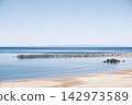 The calm blue sea and clear blue sky of summer, the coastal scenery of sandy beaches and jetties. 142973589