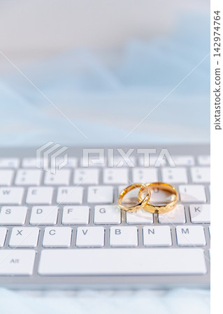 Gold wedding rings placed on a computer keyboard, representing modern wedding planning, online marriage services, digital invitations, wedding websites and technology in relationships. Gold wedding rings placed on a computer keyboard, representing modern wedding planning, online marriage services, digital invitations, wedding websites and technology in relationships. 142974764