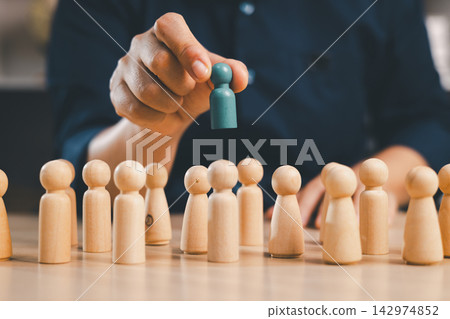 Hand selects a teal wooden figure from a crowd, representing recruitment, talent acquisition, candidate selection, hiring, standout employees, leadership potential, opportunity, and human resources. Hand selects a teal wooden figure from a crowd, representing recruitment, talent acquisition, candidate selection, hiring, standout employees, leadership potential, opportunity, and human resources. 142974852
