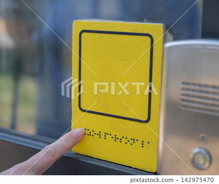 A blind woman reads the braille sign next to a call button. A blind woman reads the braille sign next to a call button. 142975470