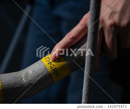 A blind woman reads the inscription on the railing of a staircase. A blind woman reads the inscription on the railing of a staircase. 142975471