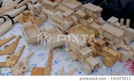Handcrafted unfinished wooden toy trucks and tools on floral cloth display, with wooden, toy, truck, handcrafted detail, showing unfinished, natural, woodgrain, wheel context Handcrafted unfinished wooden toy trucks and tools on floral cloth display, with wooden, toy, truck, handcrafted detail, showing unfinished, natural, woodgrain, wheel context 142975611