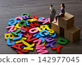 Miniature people standing next to colorful alphabet letters 142977045