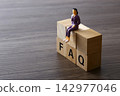 Businesswoman figurine sitting on wooden faq blocks 142977046