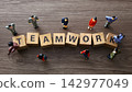 Business figurines collaborating around wooden teamwork blocks 142977049