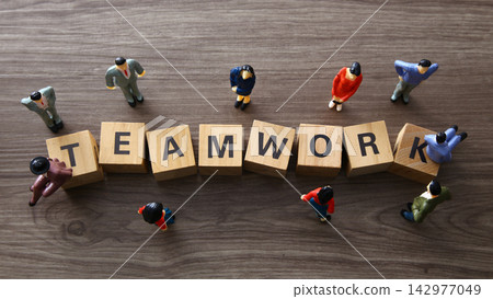 Business figurines collaborating around wooden teamwork blocks Business figurines collaborating around wooden teamwork blocks 142977049