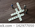 Miniature figures interacting with crossword puzzle words leadership, inspire, support, teamwork 142977050