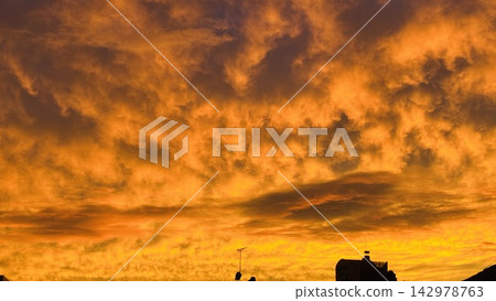壯麗的雲彩和金色的天空沐浴在夕陽的餘暉中。 壯麗的雲彩和金色的天空沐浴在夕陽的餘暉中。 142978763