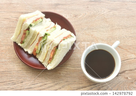 slice sandwich stuffed ham cheese with vegetable salad on plate and black coffee cup slice sandwich stuffed ham cheese with vegetable salad on plate and black coffee cup 142978792