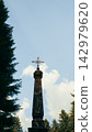 Iron cross on an old obelisk against a cloudy blue sky 142979620
