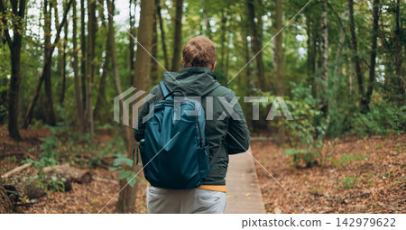 Blonde young man wearing backpack standing on autumn forest trail, hiking alone. Freedom and active lifestyle concept. High quality photo, rear wiev Blonde young man wearing backpack standing on autumn forest trail, hiking alone. Freedom and active lifestyle concept. High quality photo, rear wiev 142979622