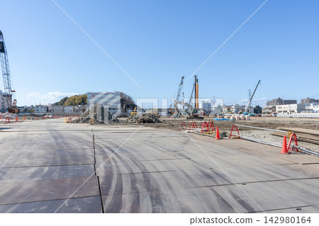 A panoramic view of a large-scale foundation and pile construction site, showing steel plates, concrete rubble, and heavy machinery. A panoramic view of a large-scale foundation and pile construction site, showing steel plates, concrete rubble, and heavy machinery. 142980164