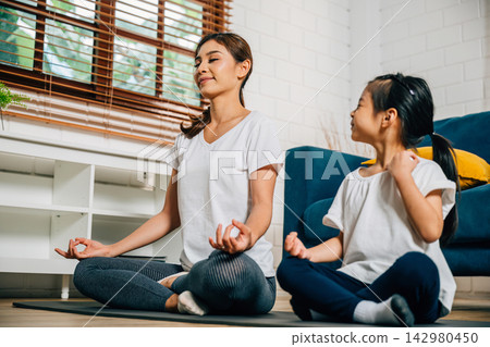 family moment a mother and her little daughter meditate and practice yoga in lotus pose 142980450