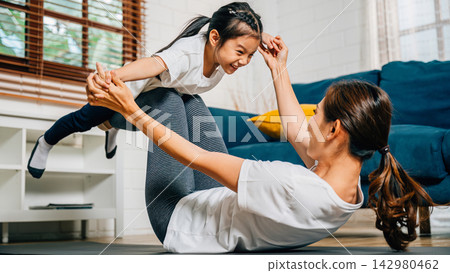 A harmonious family practices the little bird posture in yoga at home 142980462