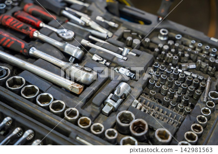 Mechanic tool set with ratchets sockets bits and wrenches in auto repair shop. Professional equipment represents car maintenance and vehicle repair service Mechanic tool set with ratchets sockets bits and wrenches in auto repair shop. Professional equipment represents car maintenance and vehicle repair service 142981563