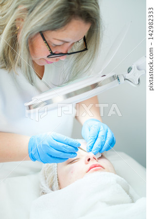 Professional esthetician performing deep pore cleansing on a client Professional esthetician performing deep pore cleansing on a client 142982333