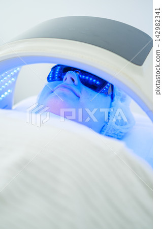 Client enjoys LED light therapy session for effective facial cleansing Client enjoys LED light therapy session for effective facial cleansing 142982341
