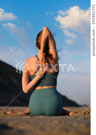 Yoga practice in Gomukhasana at sunset by the beach Yoga practice in Gomukhasana at sunset by the beach 142982355