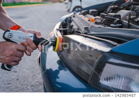 The process of polishing car headlights outdoors. The process of polishing car headlights outdoors. 142983487