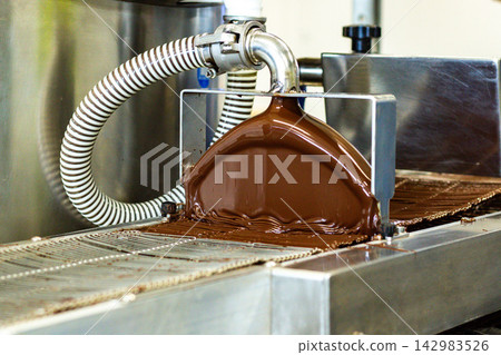 Melted chocolate glazing machine at sweets factory Melted chocolate glazing machine at sweets factory 142983526